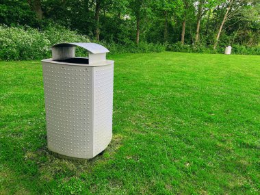 Trash bin on green grass in park. Space for text