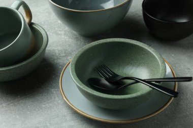 Açık gri masadaki boş bulaşık takımı ve çatal bıçak takımı, yakın plan.