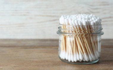 Ahşap masada cam kavanozda bir sürü pamuk tomurcuğu var.