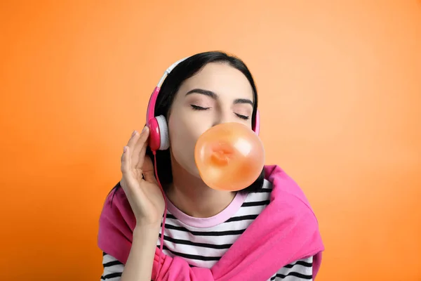Fashionable Young Woman Headphones Blowing Bubblegum Orange Background — Φωτογραφία Αρχείου