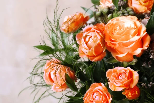 Beautiful bouquet with orange roses on beige background, closeup