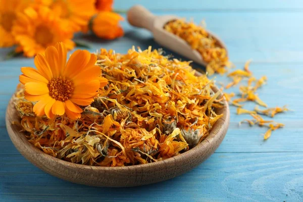 Açık mavi ahşap masadaki kuru takvim çiçekleri, yakın plan.