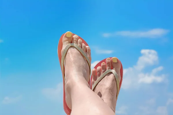 Woman in stylish pink flip flops against blue sky, closeup of feet