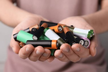 Woman holding many used electric batteries in her hands, closeup