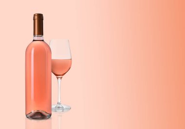 Pembe arka planda bir şişe ve bir bardak lezzetli gül şarabı. Metin için boşluk