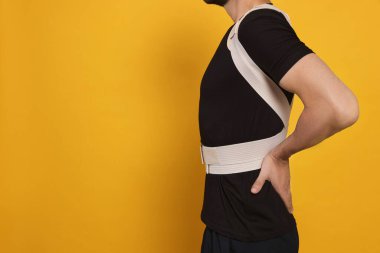 Turuncu arka planda ortopedik korsesi olan adamın yakın görüntüsü, metin için boşluk