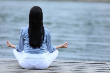 Nehir kenarında meditasyon yapan genç bir kadın. Metin için boşluk