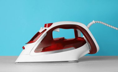 Açık mavi arka planda modern bir ütü. Ev aletleri