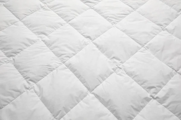 Soft quilted blanket as background, closeup view