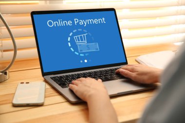 Bilgisayarla ahşap masada ödeme yapan kadın, yakın plan.