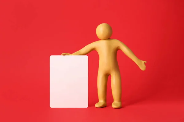 Human Figure Made Yellow Plasticine Holding Blank Sign Red Background — Stock Photo, Image