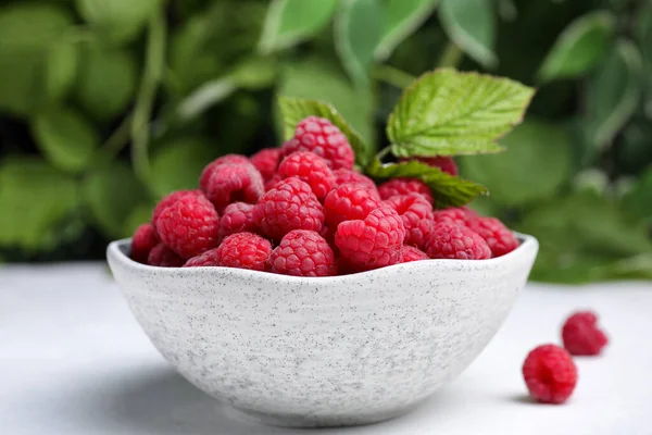 Bowl Fresh Ripe Raspberries Green Leaves White Table Blurred Background — Zdjęcie stockowe