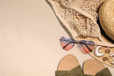 Düz kompozisyon, şık güneş gözlükleri ve diğer moda aksesuarlarla kum üzerinde yatıyordu. Metin için boşluk