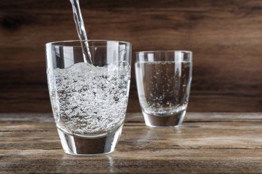 Pouring soda water into glass on wooden table. Space for text