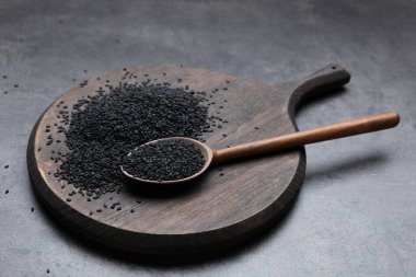 Tahta tahta, kaşık ve siyah susamlı gri masa.