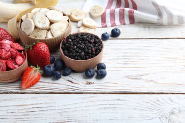 Farklı dondurulmuş kuru meyveler ve beyaz ahşap masada taze meyveler. Metin için boşluk