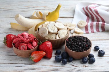 Different freeze dried and fresh fruits on white wooden table