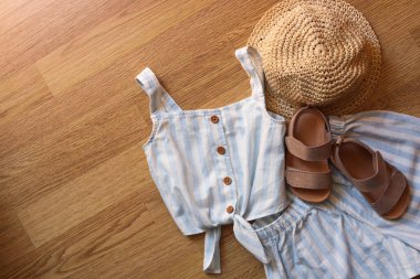 Stylish child clothes, shoes and hat on wooden background, flat lay. Space for text