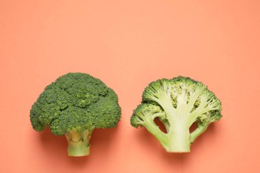 Fresh tasty broccoli on peach background, flat lay. Space for text