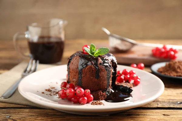 木のテーブルの上にミントとベリーとおいしい暖かいチョコレート溶岩ケーキ — ストック写真