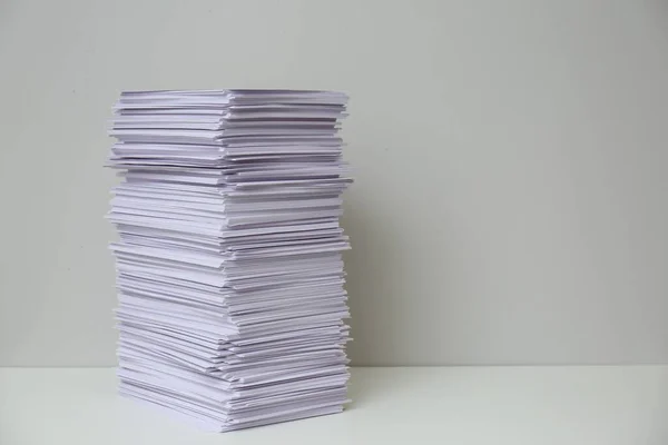 Stack of paper sheets on white table. Space for text