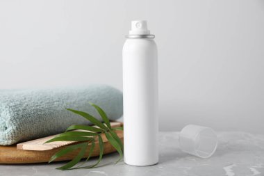 Dry shampoo spray, green twig and towel on light grey marble table