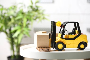 Bulanık arka planda karton kutulu oyuncak forklift. Kurye servisi