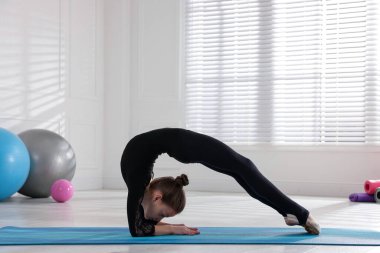 Küçük şirin kız içeride jimnastik yapıyor.