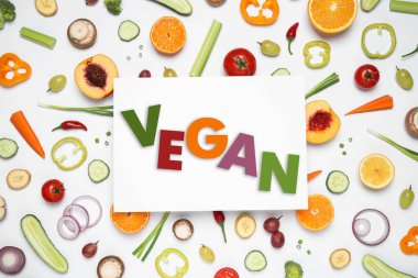 Paper card with word Vegan, fresh vegetables and fruits on white background, flat lay