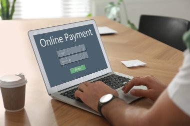 Bilgisayarı online ödeme için kullanan adam ahşap masada, yakın plan