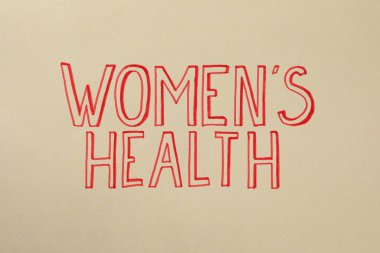 Words Women's Health written on beige background, top view