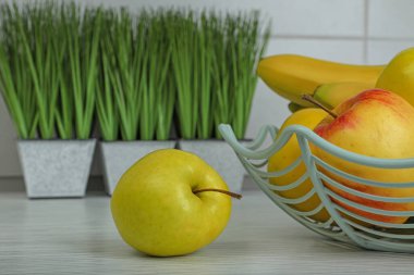 Fresh bananas, apples and houseplants on white wooden table