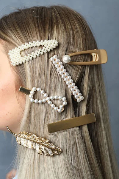 Young woman with beautiful hair clips on blue background, closeup