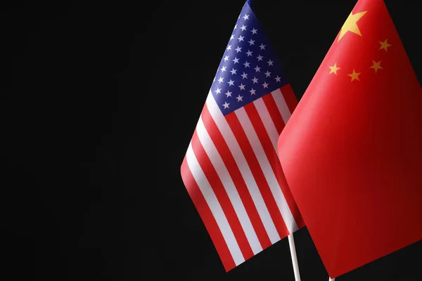 USA and China flags against black background, space for text. International relations