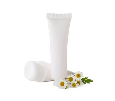 Tubes of hand cream and chamomiles on white background