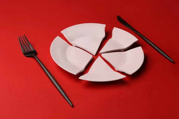 Pieces Broken Ceramic Plate Cutlery Red Background — Zdjęcie stockowe