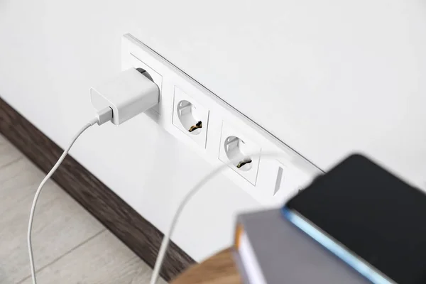 Modern smartphone charging from electric socket indoors