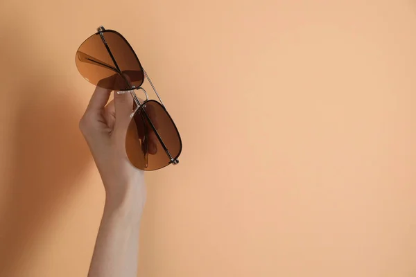 Woman Holding Stylish Sunglasses Pale Orange Background Closeup Space Text — Stock fotografie