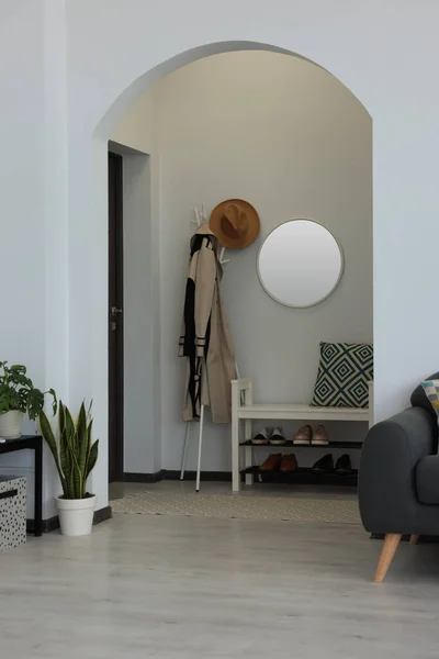 Hallway interior with clothes rack and round mirror