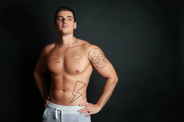 Handsome man with beautiful tattoo sketches on black background. Space for text