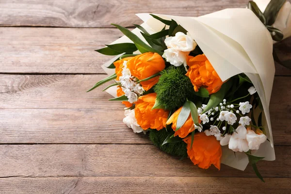 Beautiful bouquet with orange peony tulips on wooden table, above view