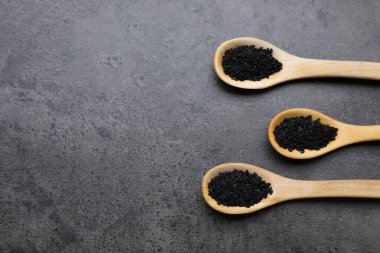 Spoons with black sesame on grey table, flat lay. Space for text