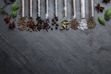 Flat lay composition with different spices and herbs on black slate table. Space for text