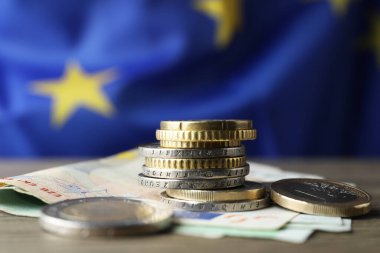 Avrupa Birliği bayrağına karşı ahşap masa üzerinde madeni para ve banknotlar, metin için yer
