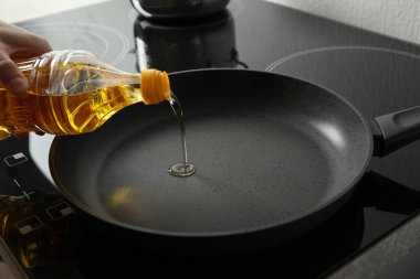 Şişeden tavaya yemek yağı döken kadın, yakın plan.