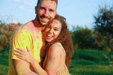 Açık havada renkli pudra boyalarıyla kaplı mutlu çift. Holi festivali kutlaması