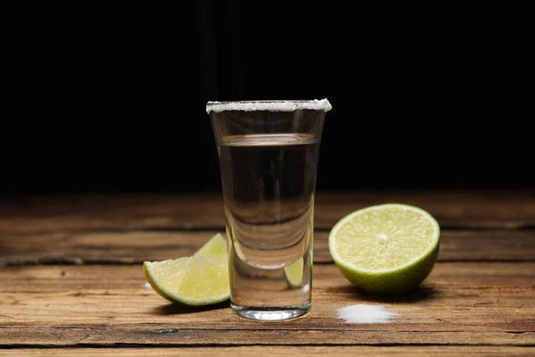 Mexican Tequila shot with salt and lime on wooden table