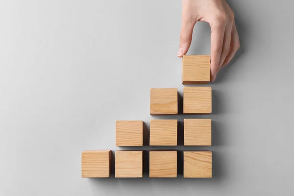 Woman Holding Wooden Cube Others Light Background Top View Management — Φωτογραφία Αρχείου