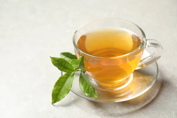 Tasse Grüner Tee Und Blätter Auf Grauem Tisch — Stockfoto