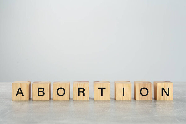 Word Abortion made of wooden cubes on grey table